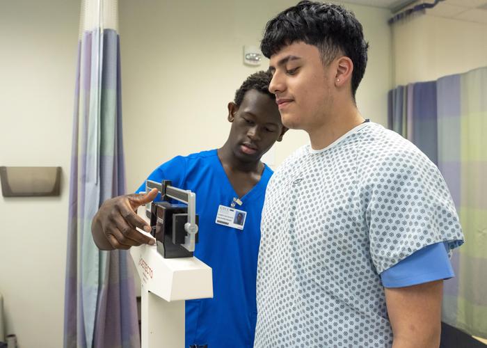 A nursing assistant takes a patient's height and weight.